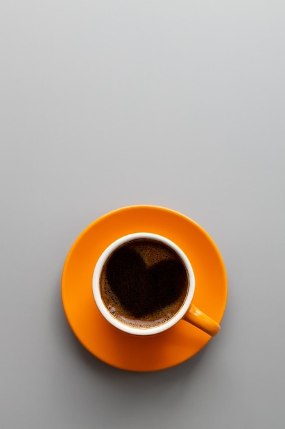 Tasse de café orange sur fond grisvue de dessusModèle vertical avec espace de copie