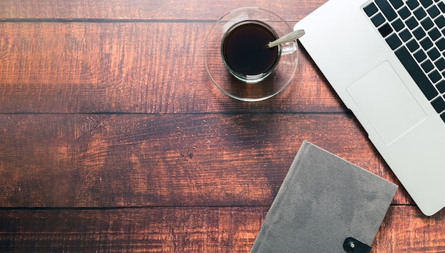 Tasse à café, ordinateur portable, livre au bureau.