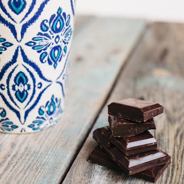 Tasse de café avec ornement bleu et chocolat sur une table en bois