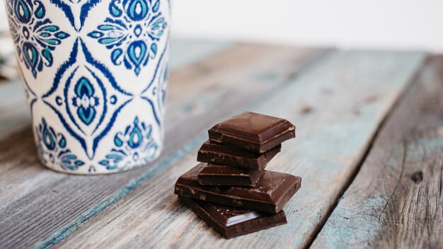 Tasse de café avec ornement bleu et chocolat sur une table en bois