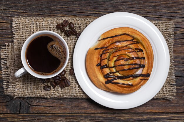 Tasse de café et pain sucré sur table en bois avec toile de jute