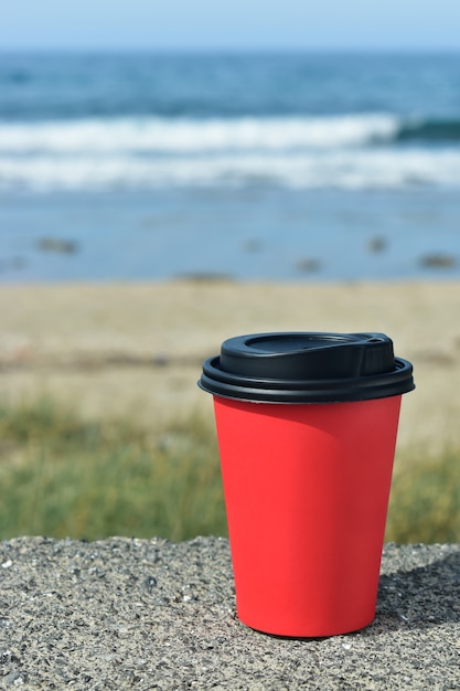 Tasse de café en papier sur le fond de la mer sur les pierres