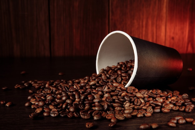 Une tasse de café en papier avec des grains de café.