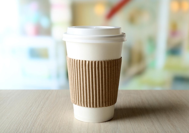 Tasse de café en papier sur la table sur fond clair