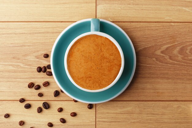 Une tasse de café parfumé en mousse sur une table en bois.