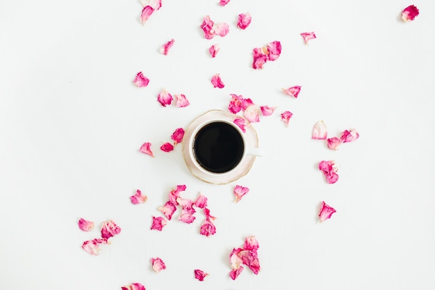 Tasse de café et pétales de rose rose sur blanc