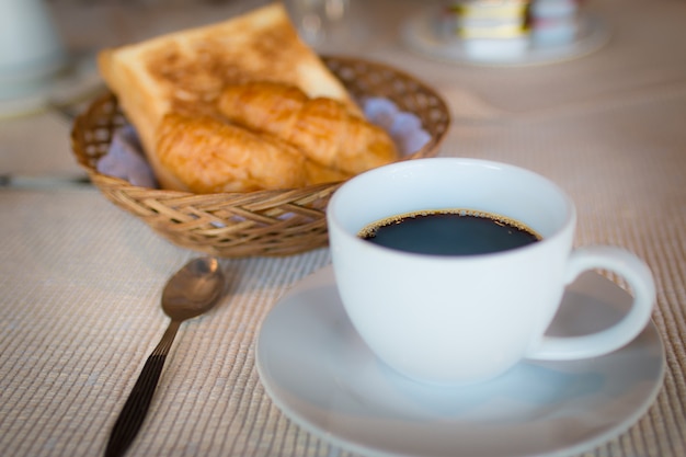 Tasse de café. Petit déjeuner avec du café et des croissants dans un panier sur la table.