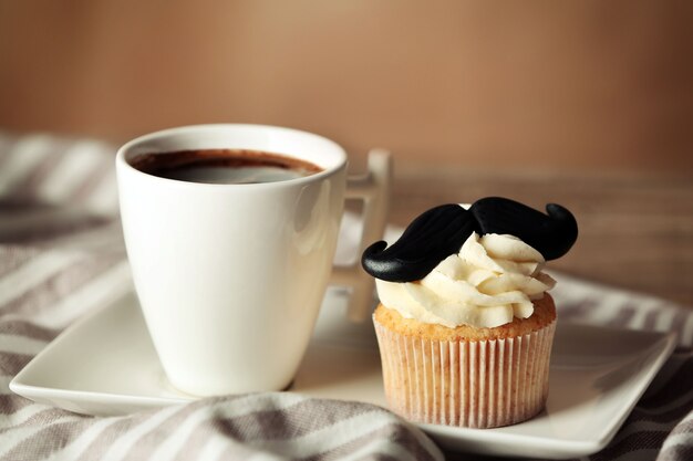 Tasse de café et petit gâteau avec moustache sur serviette gros plan