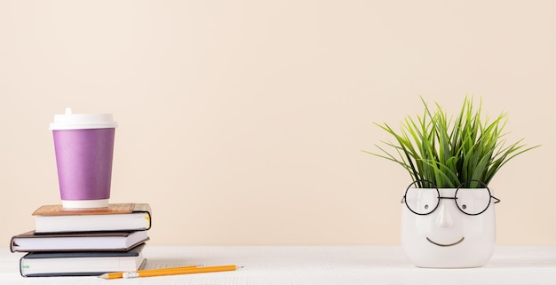 Tasse à café sur pile de blocs-notes et plante