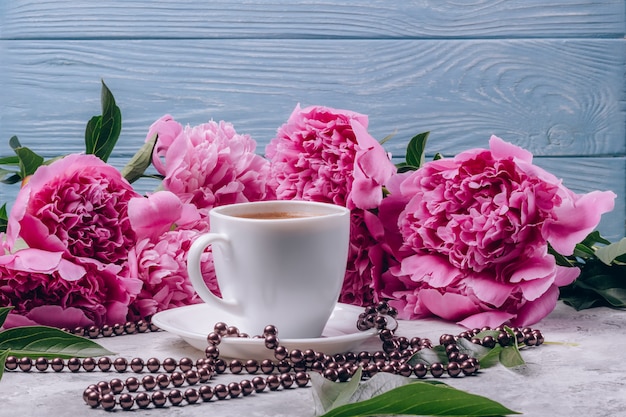 Une tasse de café avec des pivoines roses luxuriantes