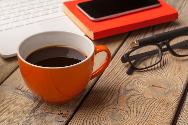 Une tasse de café sur la plaque orange sur la table en bois. Intérieur de bureau