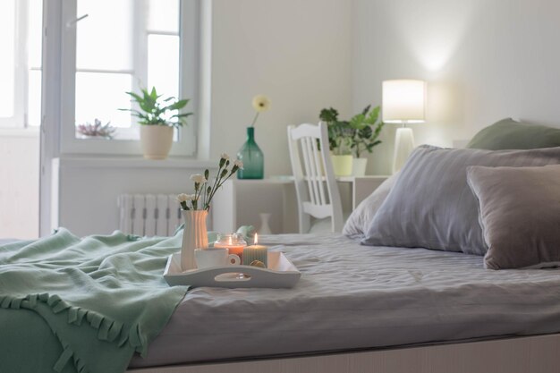 Tasse de café sur un plateau en bois sur le lit avec des fleurs et des bougies