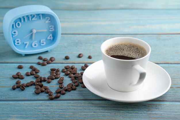 Tasse à café et réveil bleu sur table en bois.