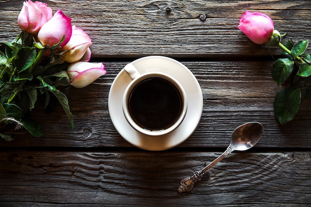 Tasse de café avec rose rouge et espace copie sur fond de bois. petit-déjeuner le jour de la fête des mères, de la femme, de la Saint-Valentin ou de la naissance. boisson chaude, fleurs