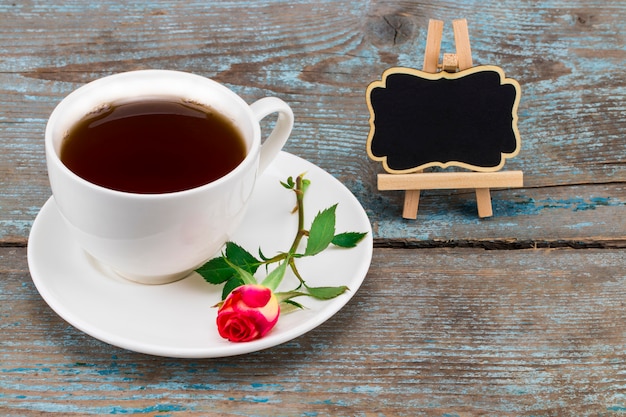 Tasse à café et rose rouge avec tableau noir avec un espace vide pour un texte sur bois