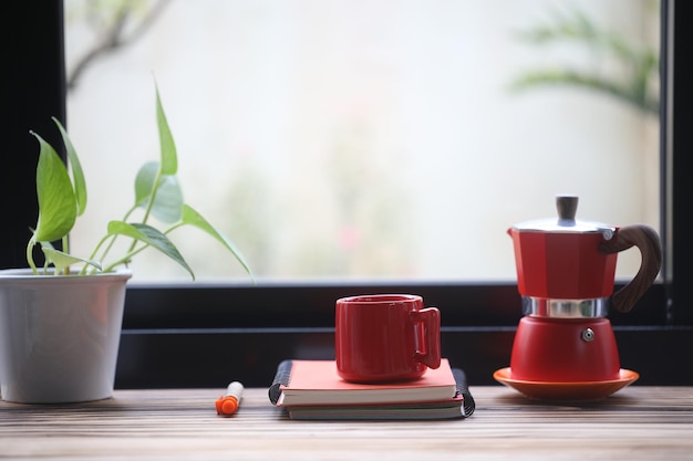 Une tasse de café rouge et un pot de moka rouge avec un cahier rouge