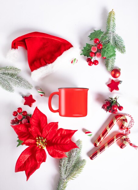 Photo une tasse de café rouge vierge en blanc simulant une branche de sapin, une poinsettia, une canne à bonbons et des jouets noël, nouvel an