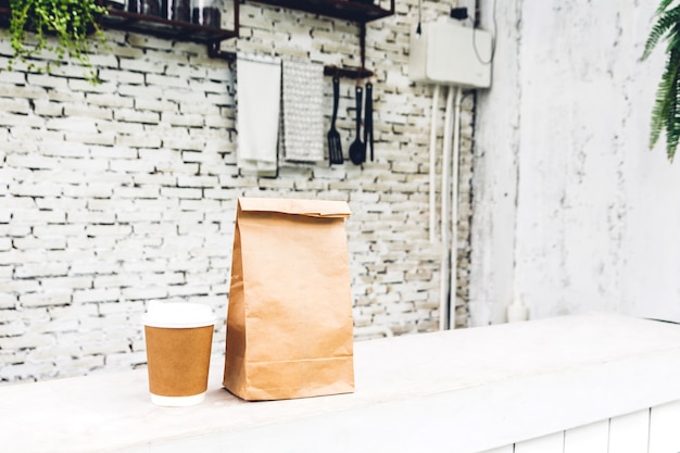 Tasse de café et sac en papier blanc avec espace de copie pour votre marque sur table