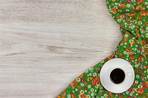 Tasse à café et serviette en tissu floral sur fond en bois.