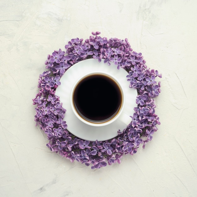 Une Tasse Avec Un Café Sur Une Soucoupe, Entourée De Fleurs Lilas En Surface