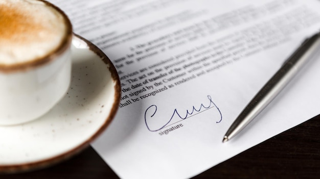 Tasse de café avec stylo à bille en mousse contrat vierge sur une table en bois