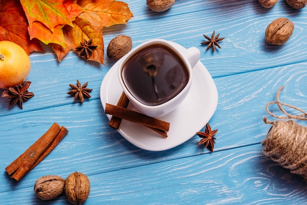 Une tasse de café sur une table bleue avec des pommes