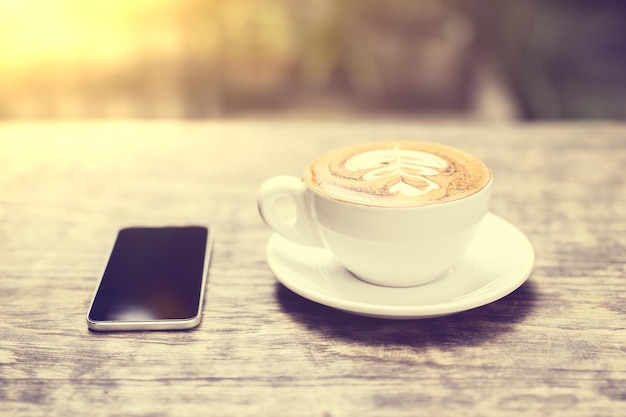 Tasse de café et téléphone portable sur une table à l'extérieur