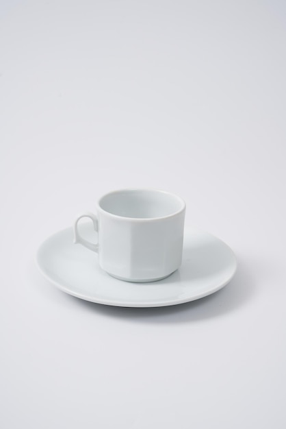 Tasse de café ou de thé en céramique blanche et son assiette sur fond blanc