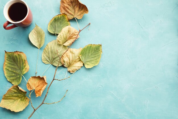 Tasse de café ou de thé chaud et feuilles d'automne sur le mur bleu. Délices de l'automne.