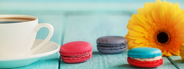 Tasse de café ou de thé avec une fleur jaune et macarons sur fond bleu