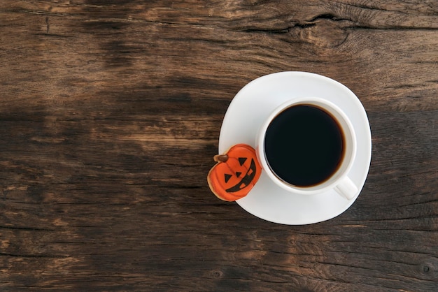 Tasse de café ou de thé noir et pain d'épice d'Halloween en forme de citrouille sur une table en bois marron Espace pour le texte Vue de dessus