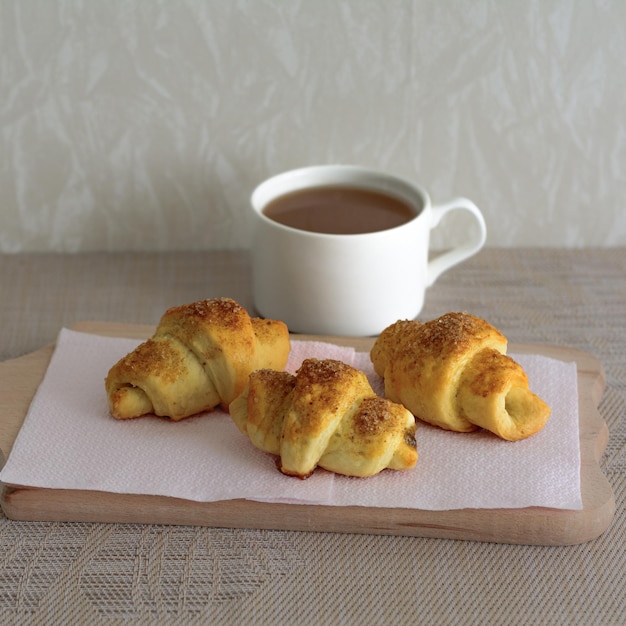 Une tasse de café et trois croissants sur un support en bois Petit-déjeuner Croissants faits maison