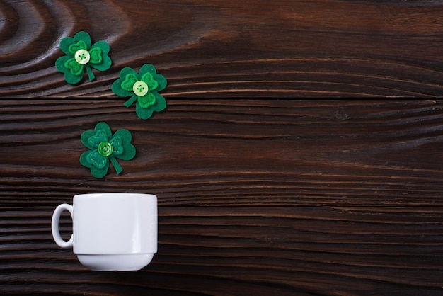 Tasse à café avec trois feuilles faites à la main de trèfle à feuilles sur fond de bois