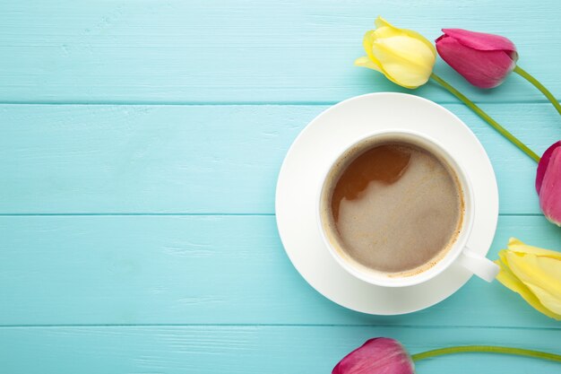 Tasse de café avec des tulipes sur une surface bleue