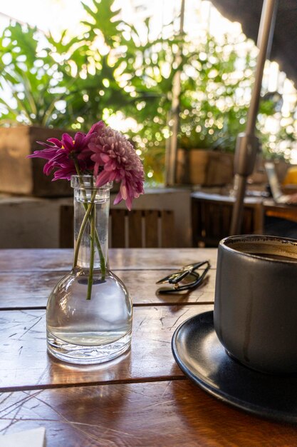 Tasse de café avec végétation de table en bois d'argile noire en arrière-plan et fleurs