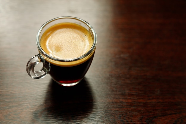 Une tasse de café en verre avec expresso près de la fenêtre le matin