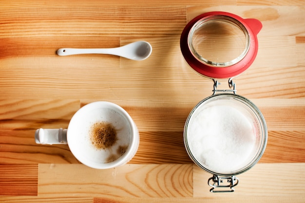 Tasse de café et verre de sucre sur une table en bois avec une lumière douce