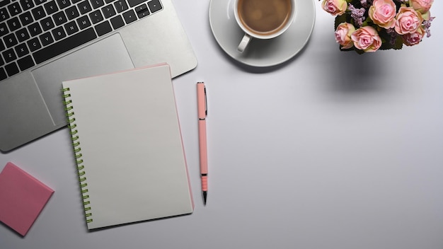 Tasse à café vide pour ordinateur portable et pense-bête sur un bureau blanc