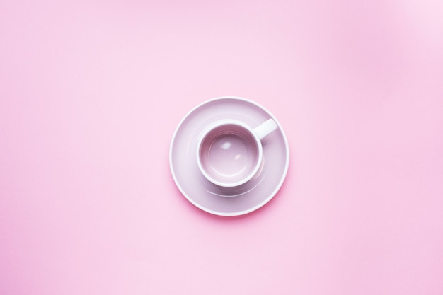 Une tasse de café vide avec une soucoupe au centre de la table sur un fond rose avec copie espace. Vue de dessus. minimalisme.