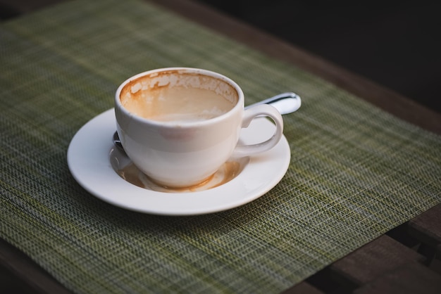 Tasse à café vide avec des timbres de mousse de lait et une légère empreinte de rouge à lèvres sur les bords de la table