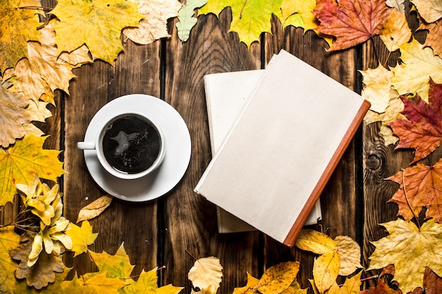 Tasse de café avec un vieux livre et des feuilles d'érable