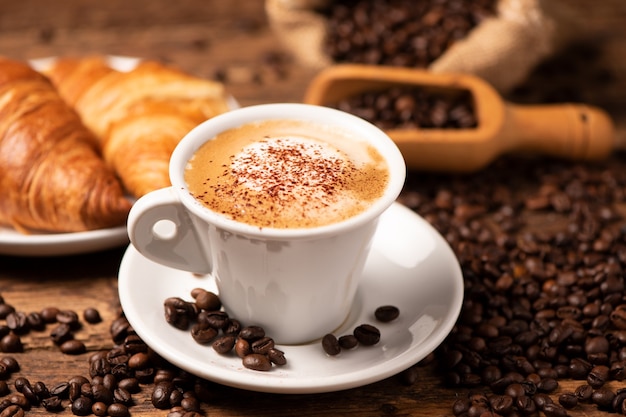 Photo une tasse de cappuccino avec des grains de café en arrière-plan close up