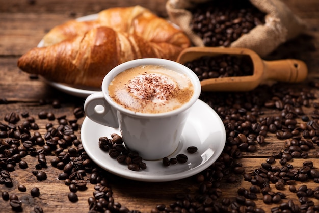 Une tasse de cappuccino avec des grains de café en arrière-plan close up