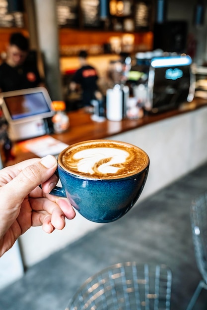 Une tasse de cappuccino à la main Une tasse de café chaud sur le fond d'une table de café