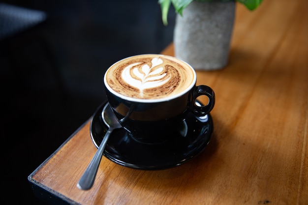 Tasse de cappuccino savoureux avec art latte sur fond de table en bois.