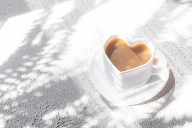 Une tasse de cappuccino sur une soucoupe et à l'ombre du soleil