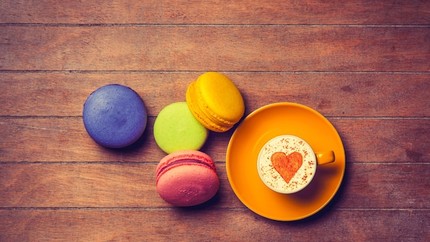 Tasse de cappuccino avec symbole en forme de coeur et macarons sur bois