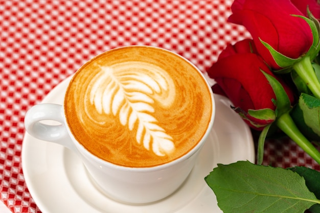 Tasse de cappucino avec art et bouquet de roses sur table en bois se bouchent