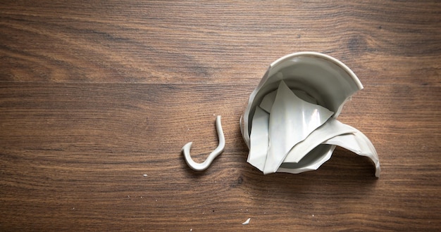 Tasse cassée blanche sur le fond en bois