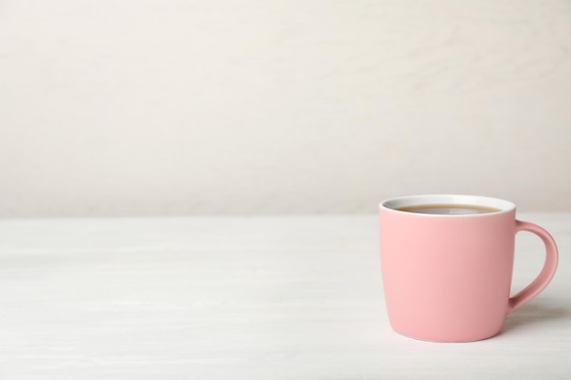 Tasse en céramique rose avec café aromatique chaud sur table